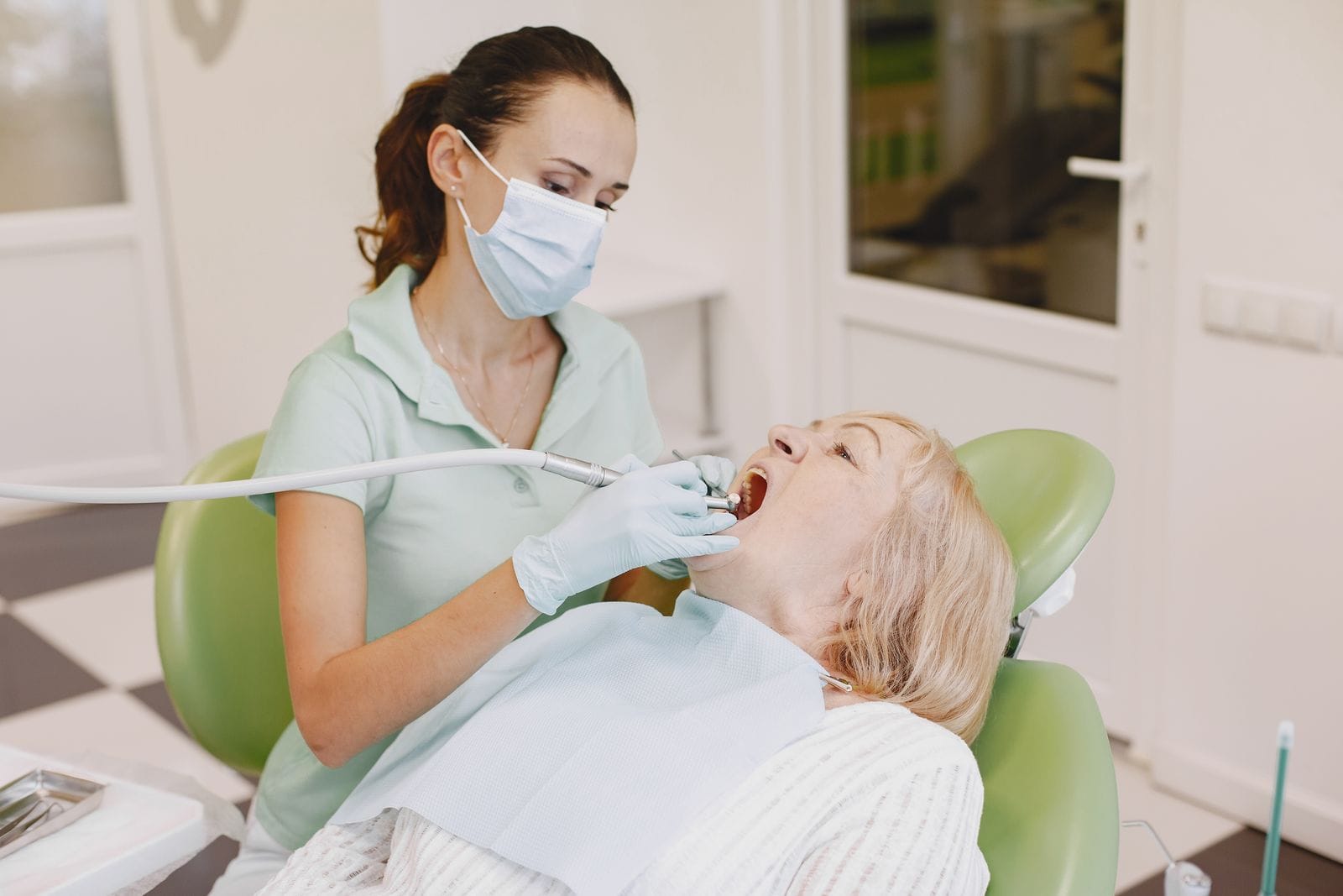Dentist examining an older patient's teeth in a clinic
