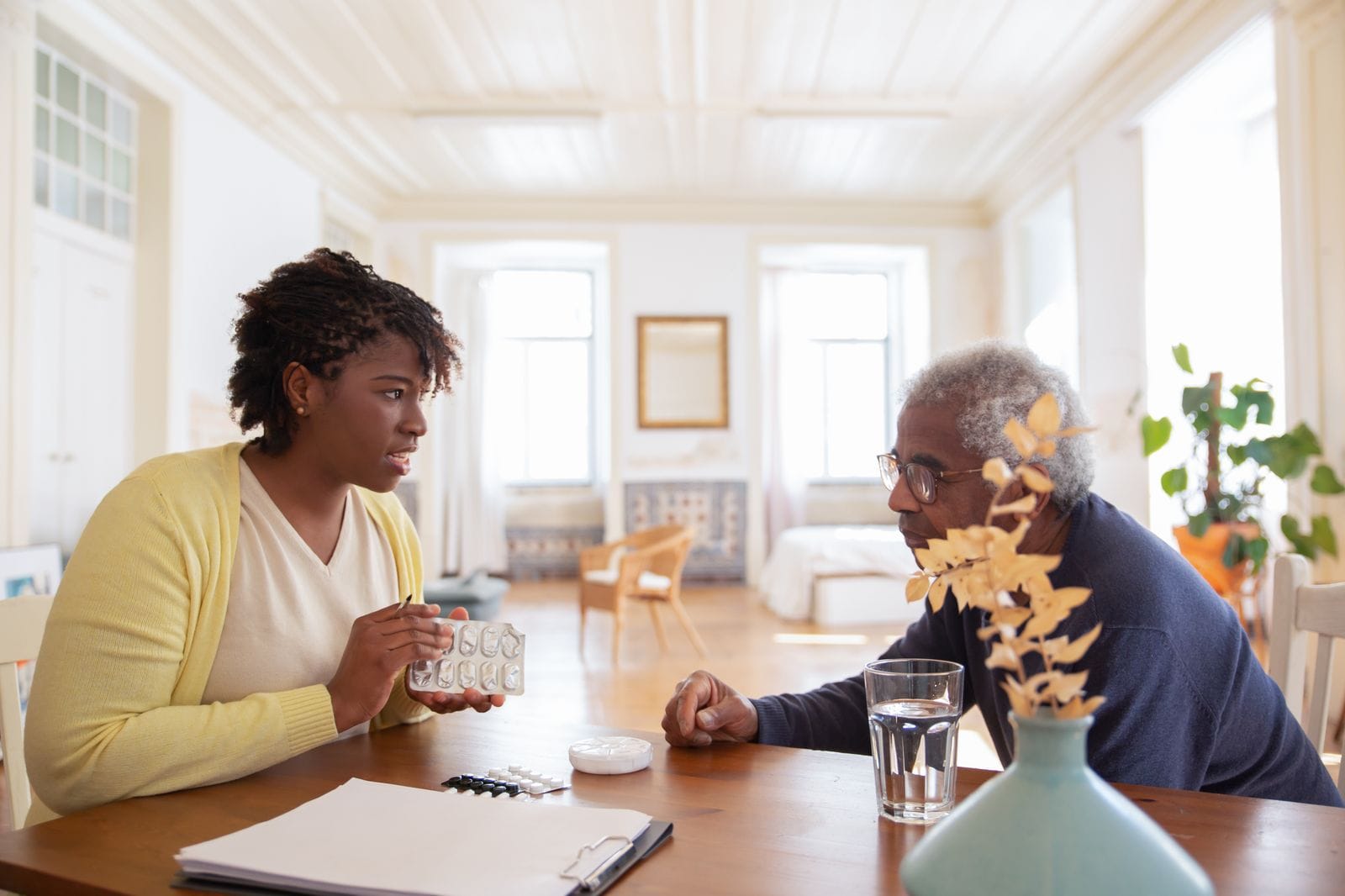 Medicare Part D Prescription Drug Coverage Explained 1 Senior man discussing medication at a table with a caregiver