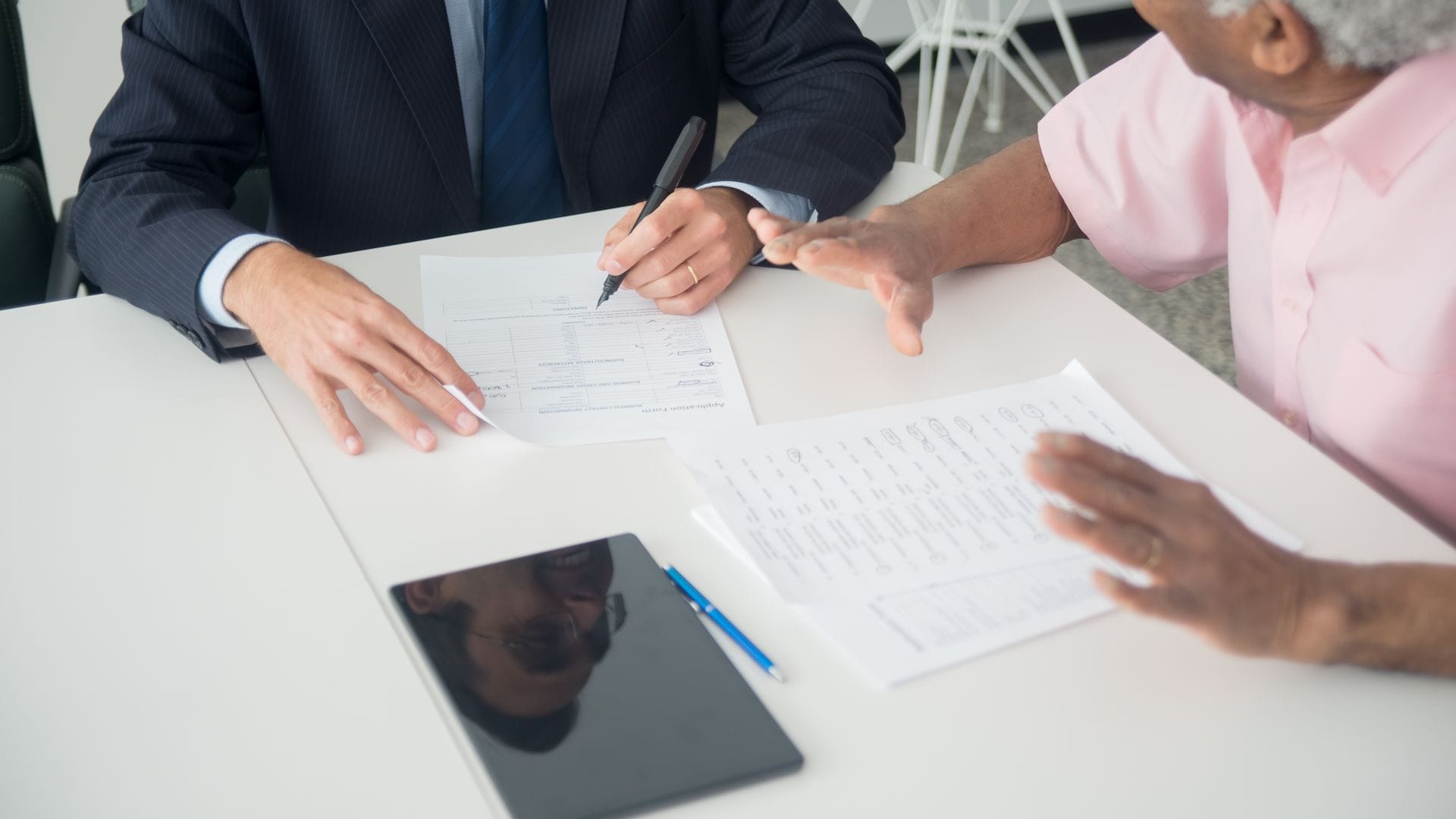 What to Bring to an Annual Insurance Review 1 Older client and insurance advisor reviewing documents at an office table