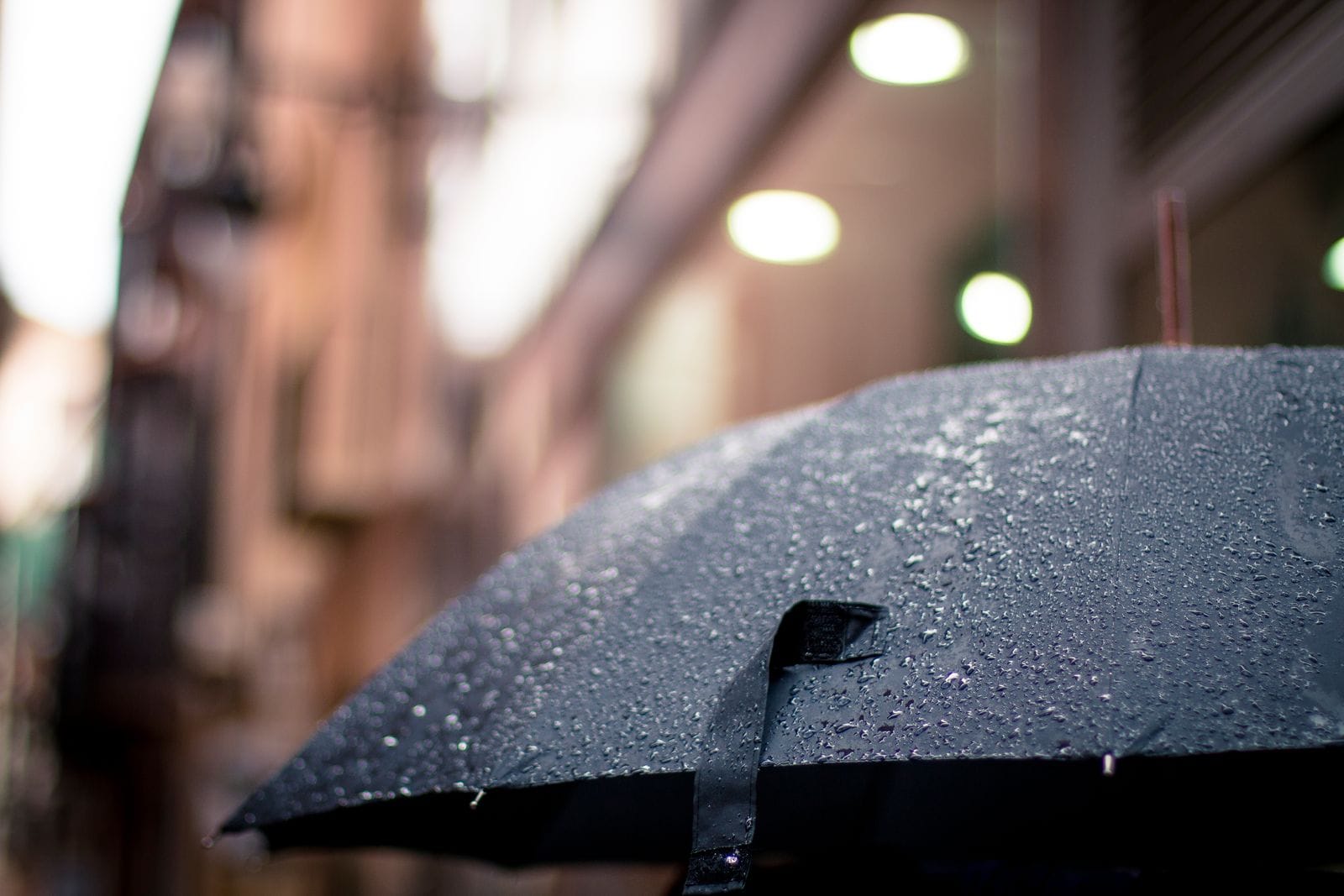 Close-up of a blue umbrella covered with raindrops.