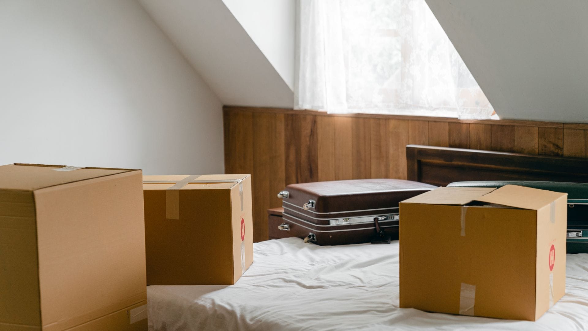 Cardboard boxes and suitcases arranged on a bed in a bedroom