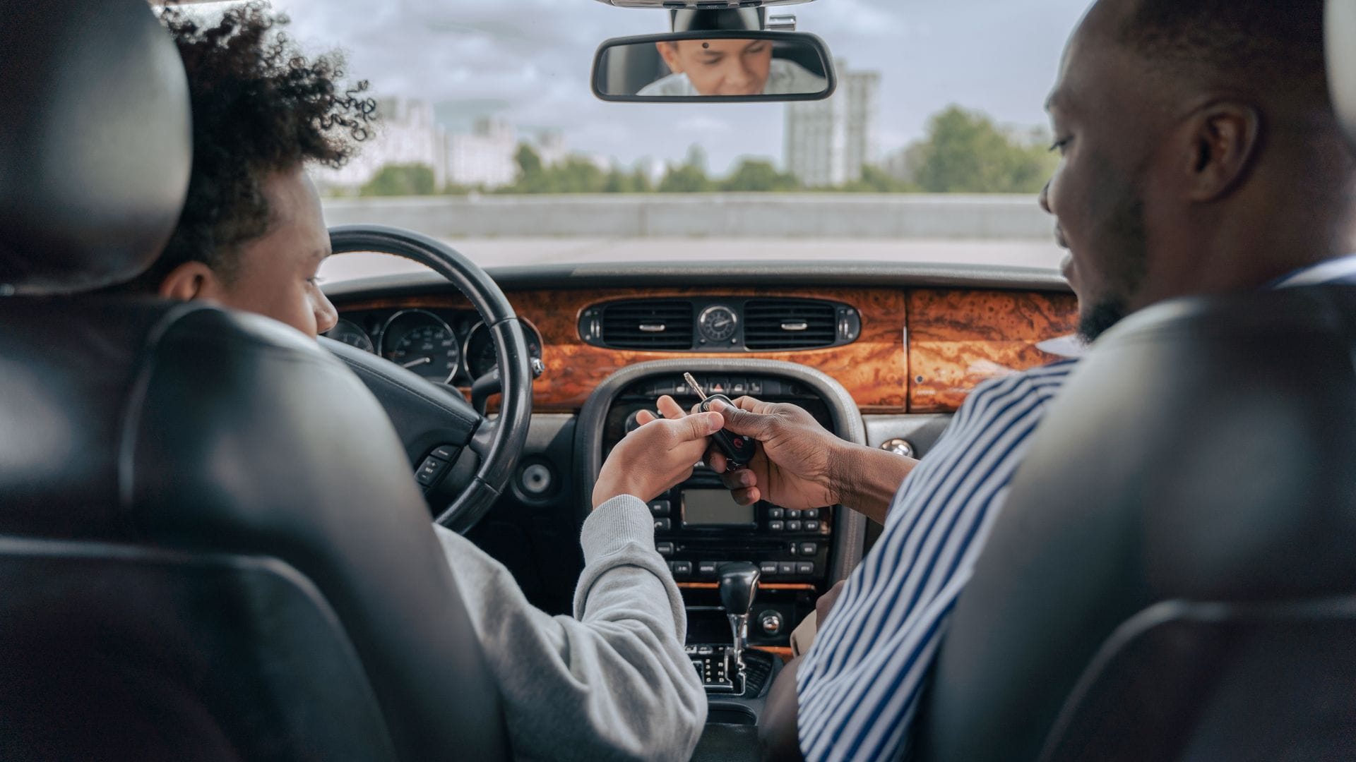 Father guiding his teenage son during a driving lesson inside a car