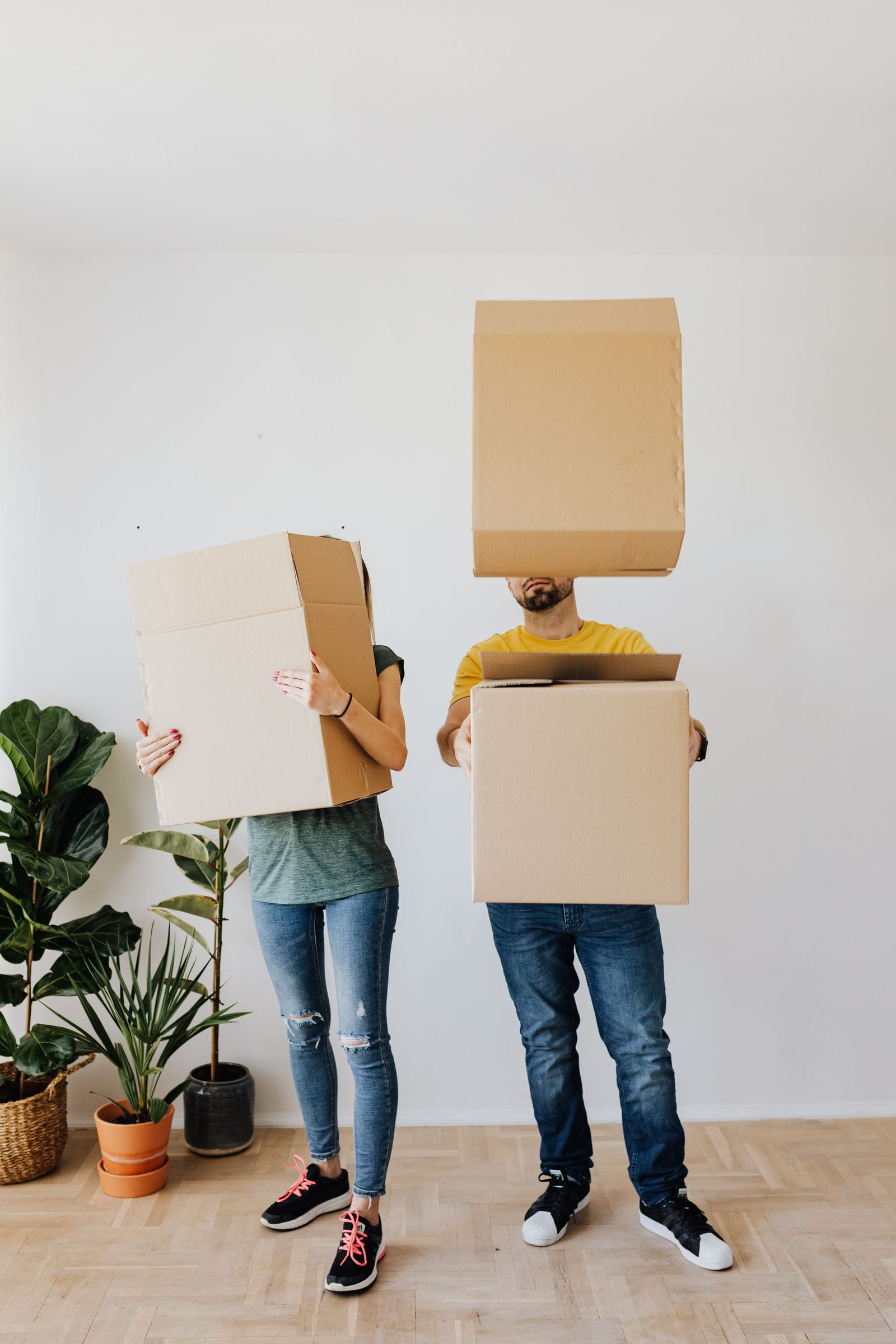 Two people carrying cardboard moving boxes indoors