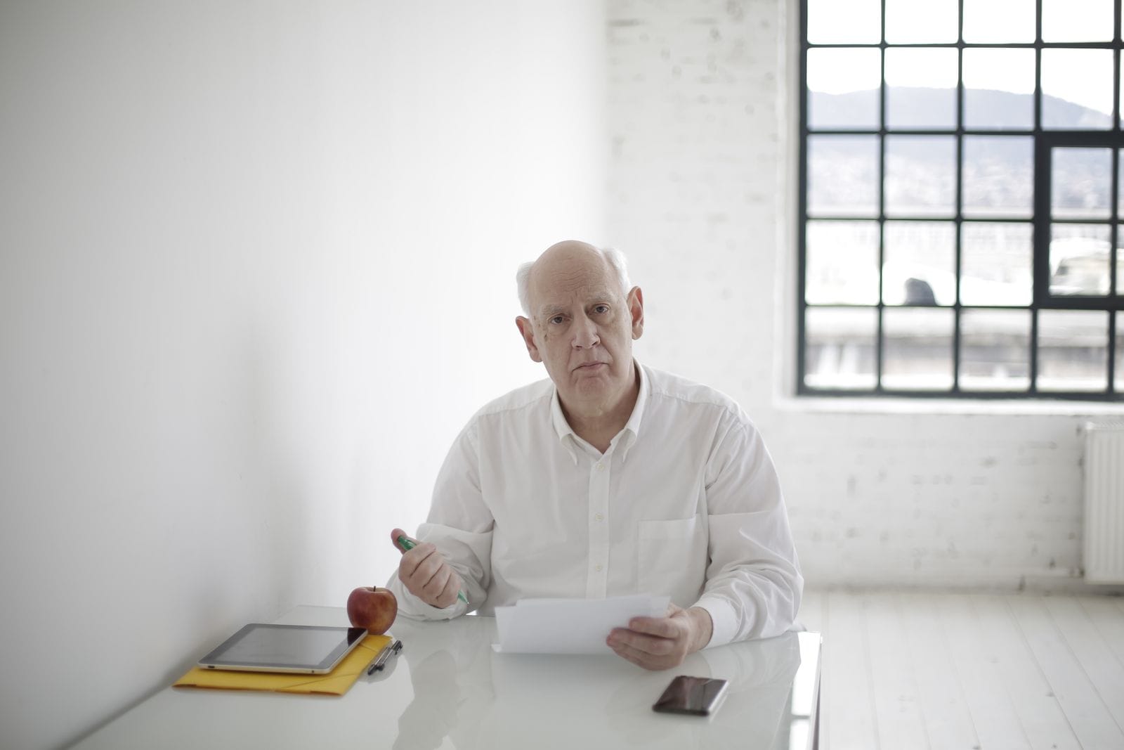 Older man reviewing paperwork at an office desk