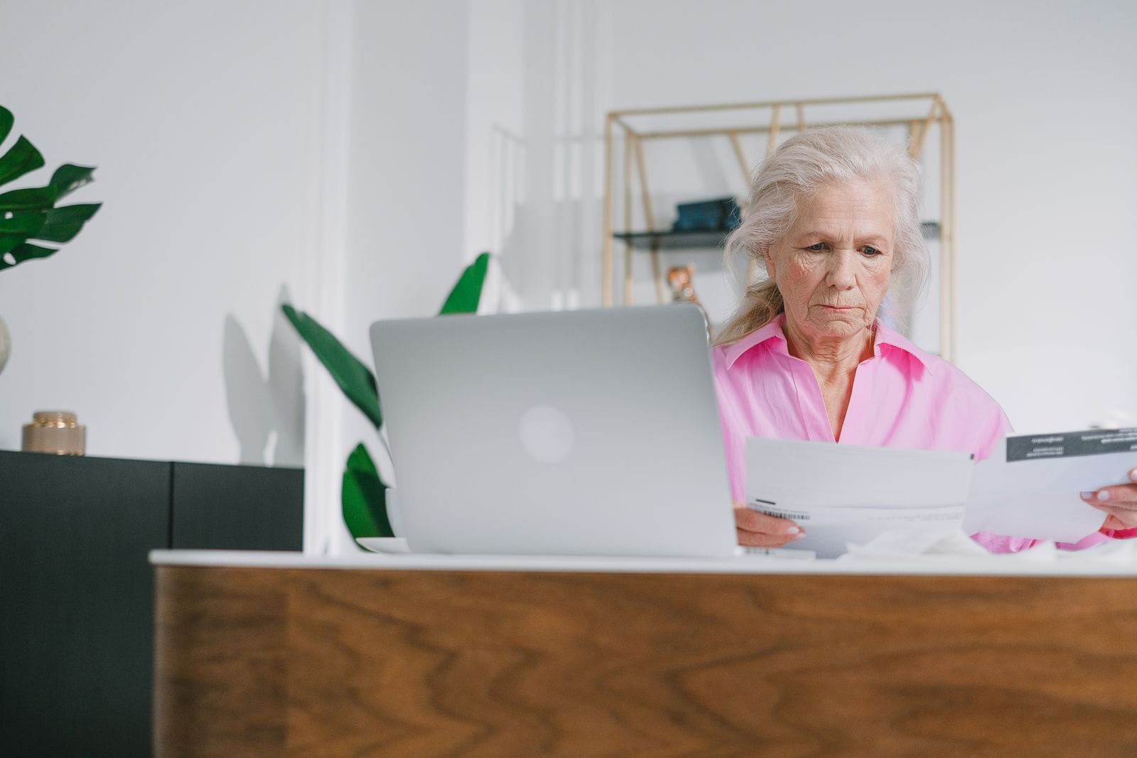 Older woman reviewing documents beside a laptop