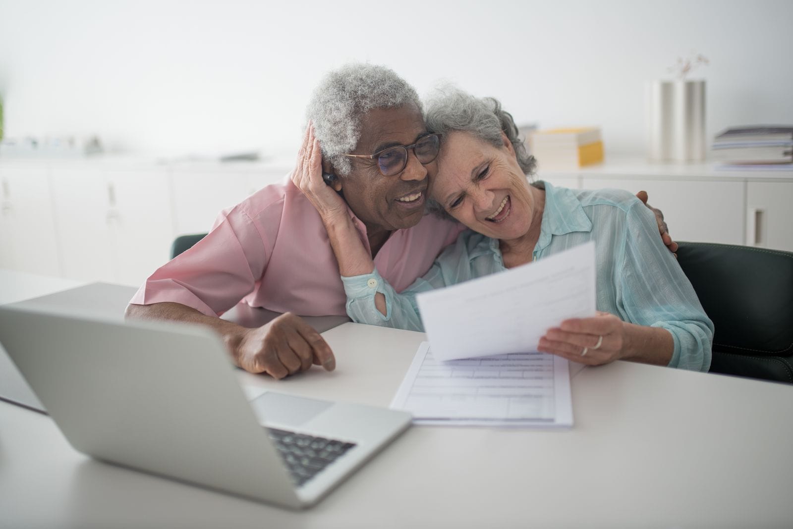 Older couple smiling while reviewing a document at a desk